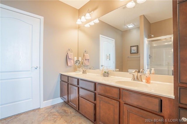 full bath with baseboards, a shower with door, a sink, and double vanity