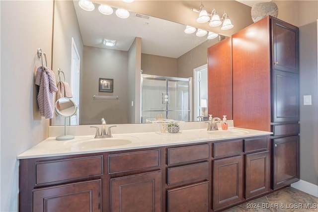 bathroom featuring double vanity, a stall shower, baseboards, and a sink