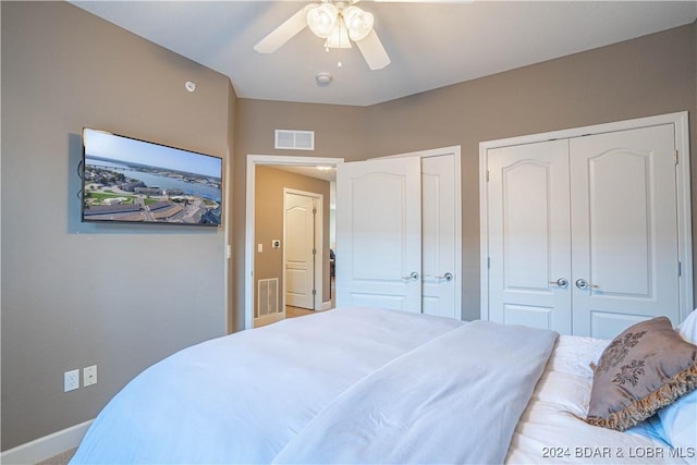 bedroom featuring ceiling fan, baseboards, visible vents, and multiple closets