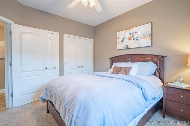 bedroom with ceiling fan, two closets, and light colored carpet