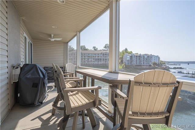 view of patio featuring a water view, a ceiling fan, and area for grilling