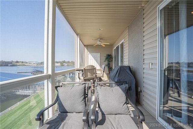 sunroom / solarium with a ceiling fan and a water view