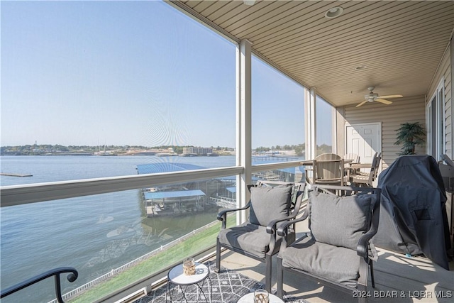 balcony with a sunroom, a water view, and ceiling fan