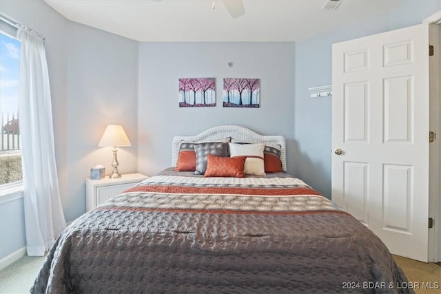 bedroom with ceiling fan, light colored carpet, and multiple windows