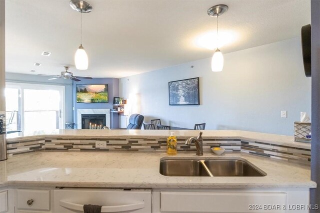 kitchen featuring white cabinets, decorative light fixtures, white dishwasher, and sink