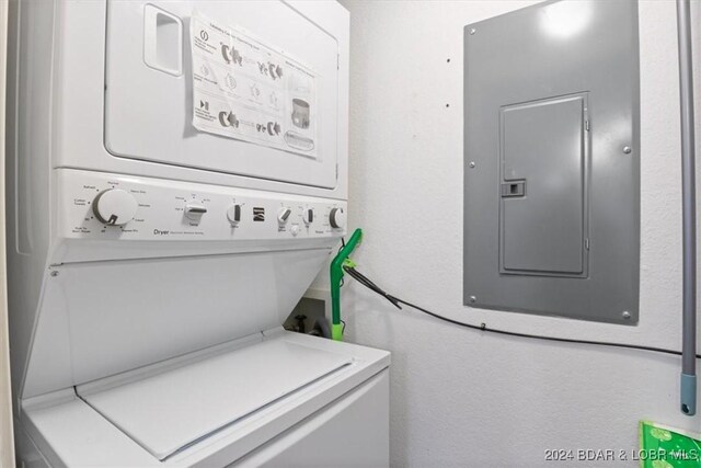 laundry room with electric panel and stacked washer and clothes dryer