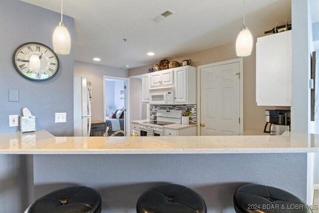 kitchen with kitchen peninsula, white cabinets, pendant lighting, and white appliances