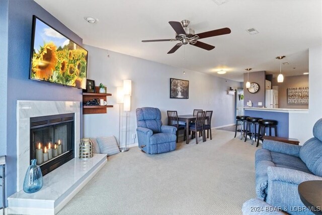 carpeted living room with ceiling fan and a high end fireplace