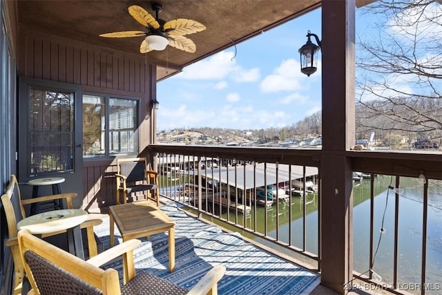 snow covered back of property featuring ceiling fan and a water view