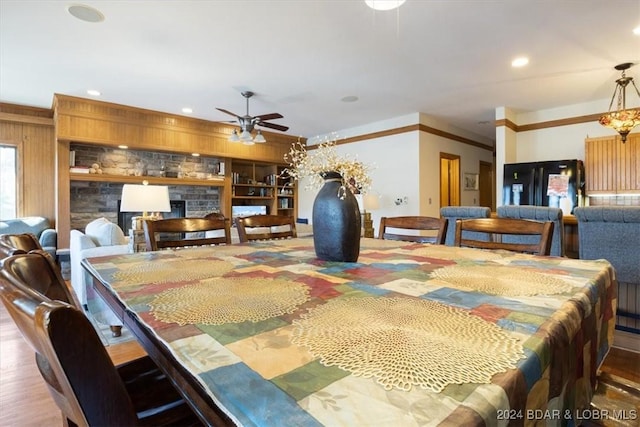 dining area with a fireplace, wood-type flooring, ceiling fan, and crown molding