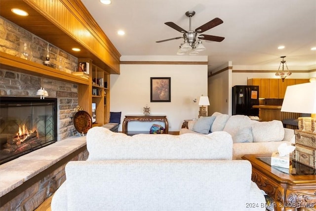 living room with ceiling fan, a fireplace, and ornamental molding