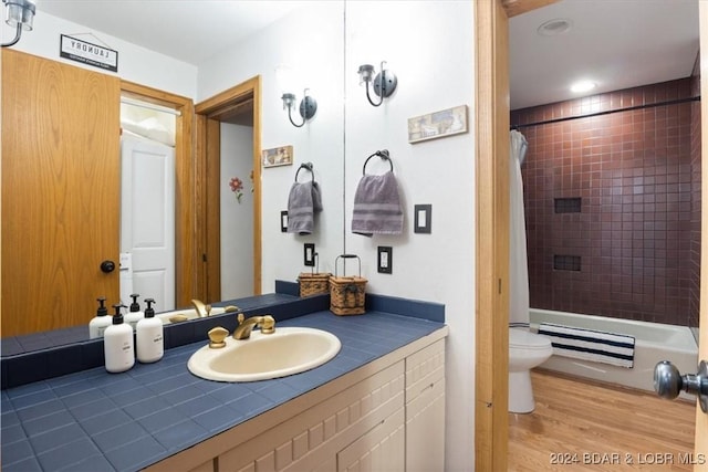 full bathroom with hardwood / wood-style flooring, vanity, toilet, and shower / tub combo