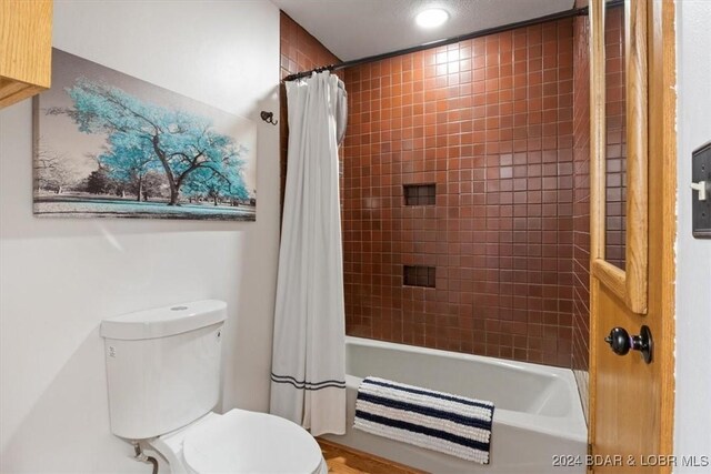 bathroom with toilet and shower / tub combo with curtain