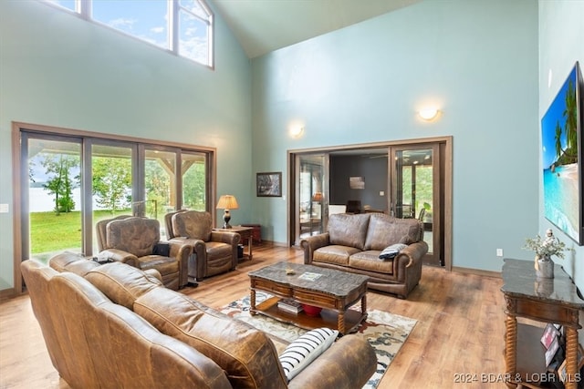 living room featuring light wood-type flooring, high vaulted ceiling, and a wealth of natural light