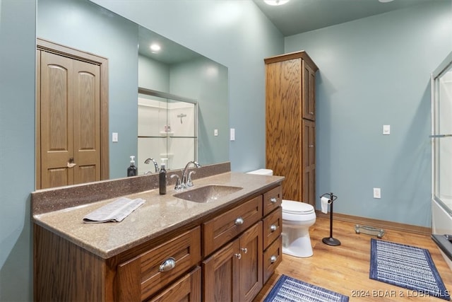 bathroom with vanity, hardwood / wood-style flooring, toilet, and a shower with door