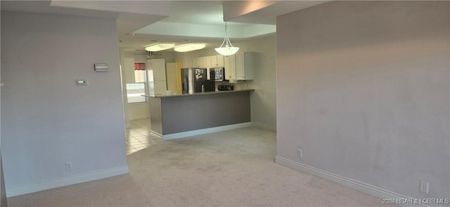 kitchen featuring kitchen peninsula, white cabinets, pendant lighting, and light colored carpet