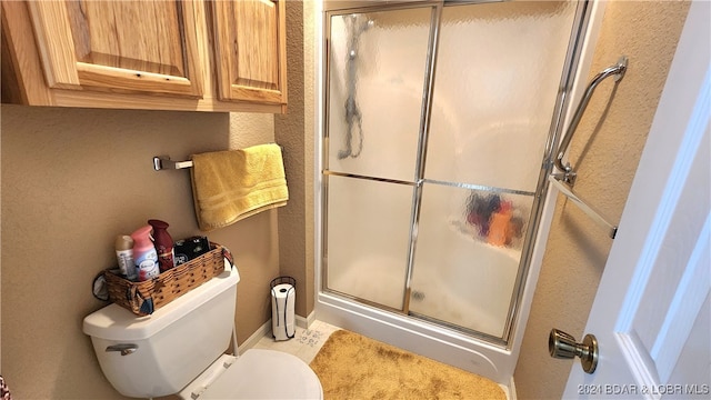 bathroom with toilet and a shower with door