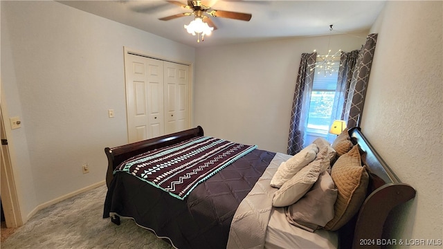 carpeted bedroom featuring a closet and ceiling fan with notable chandelier