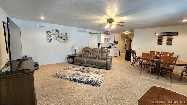 carpeted living room featuring ceiling fan and a textured ceiling