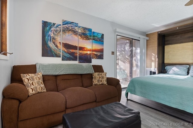 bedroom with hardwood / wood-style flooring, access to exterior, and a textured ceiling