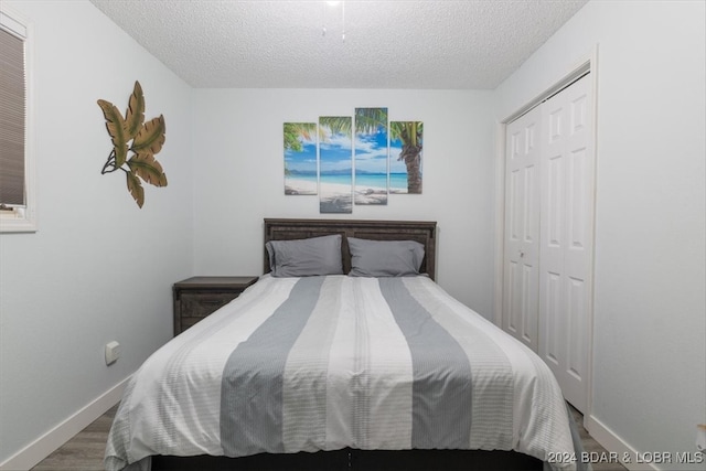 bedroom featuring hardwood / wood-style floors, a textured ceiling, and a closet