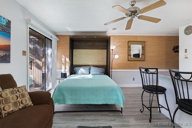 bedroom featuring hardwood / wood-style flooring, ceiling fan, crown molding, and a textured ceiling