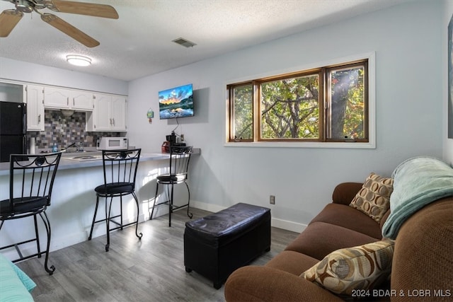 living room featuring ceiling fan, sink, a textured ceiling, and hardwood / wood-style flooring