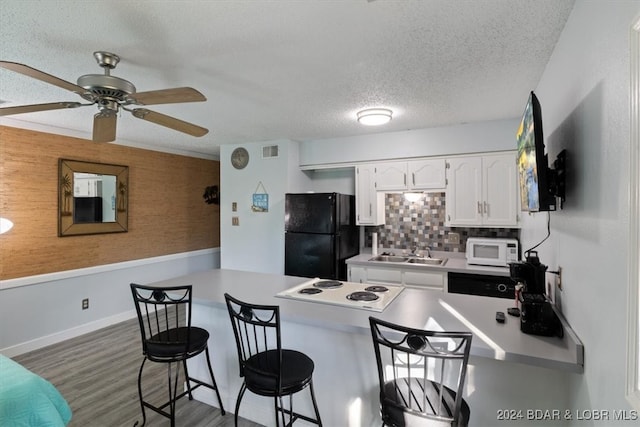 kitchen with a kitchen bar, kitchen peninsula, white appliances, sink, and white cabinetry