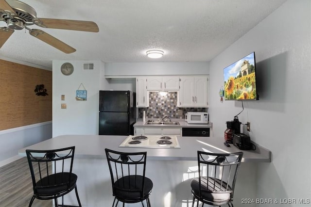 kitchen featuring white appliances, white cabinets, a kitchen breakfast bar, ceiling fan, and a textured ceiling