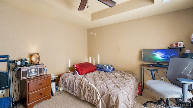 carpeted bedroom with ceiling fan and a tray ceiling