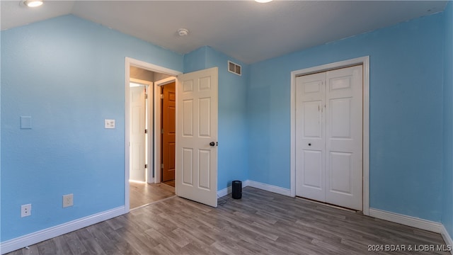 unfurnished bedroom featuring a closet, vaulted ceiling, and hardwood / wood-style flooring