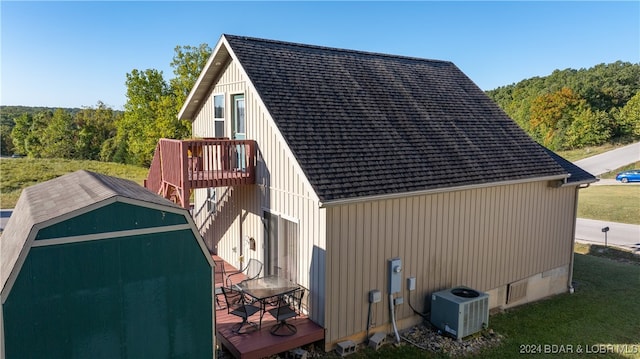 view of side of home featuring central air condition unit, a yard, and a wooden deck