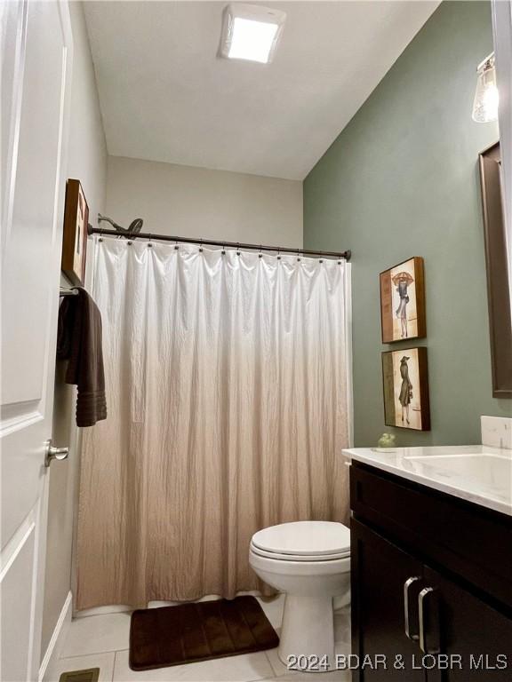 bathroom featuring lofted ceiling, vanity, toilet, and tile patterned flooring