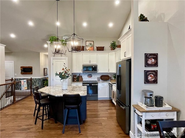 kitchen with pendant lighting, appliances with stainless steel finishes, a center island, white cabinets, and light wood-type flooring