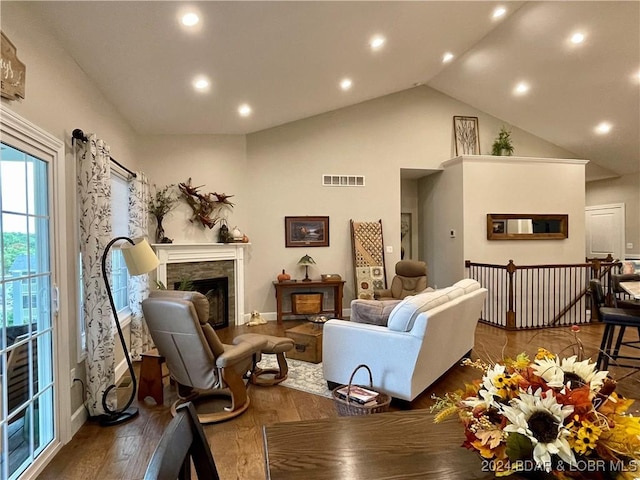 living room featuring high vaulted ceiling, hardwood / wood-style floors, and a fireplace