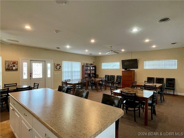 kitchen featuring white cabinetry, a center island, ceiling fan, and dark colored carpet