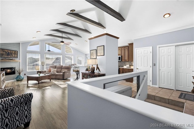 living room featuring high vaulted ceiling, ornamental molding, ceiling fan, light hardwood / wood-style floors, and beam ceiling