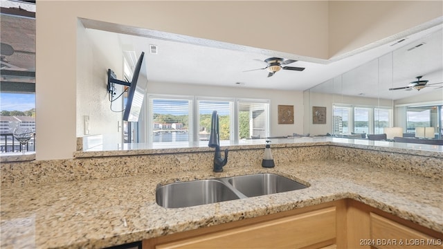 kitchen featuring light brown cabinetry, light stone countertops, sink, and a healthy amount of sunlight