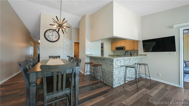 kitchen featuring a kitchen breakfast bar, kitchen peninsula, dark hardwood / wood-style flooring, and high vaulted ceiling