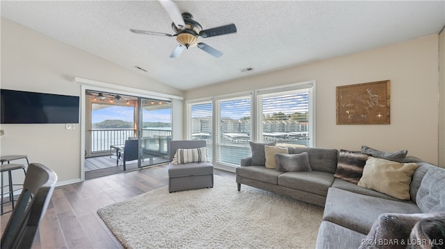 living room featuring ceiling fan, hardwood / wood-style flooring, lofted ceiling, and a textured ceiling