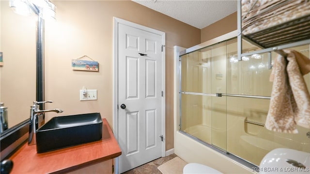 full bathroom with shower / bath combination with glass door, vanity, toilet, and a textured ceiling