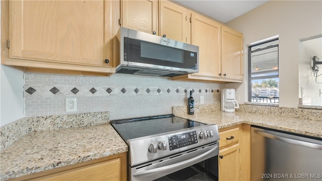 kitchen featuring stainless steel appliances, light stone countertops, light brown cabinets, and tasteful backsplash