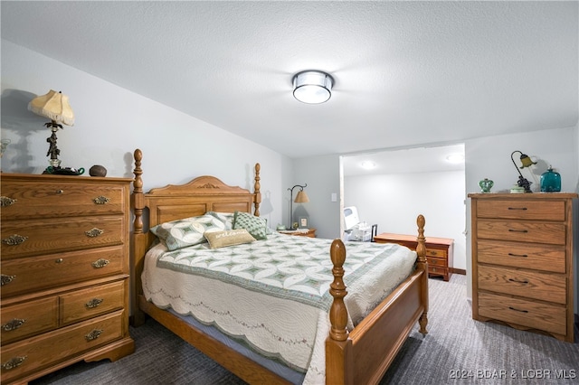 bedroom featuring a textured ceiling and dark carpet