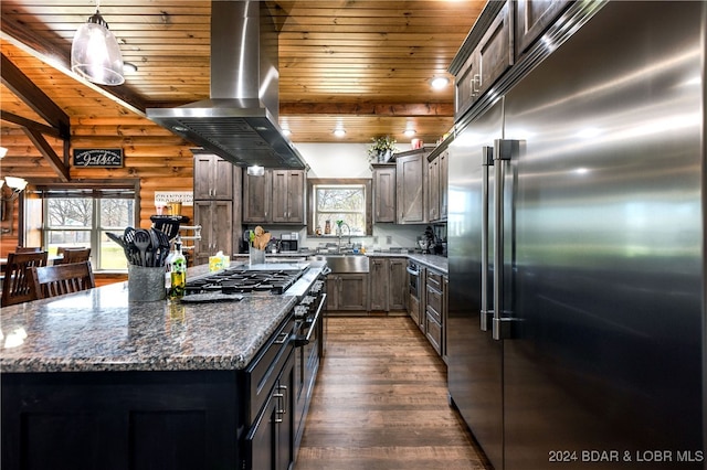 kitchen featuring dark hardwood / wood-style floors, a kitchen island, built in refrigerator, island exhaust hood, and wooden walls