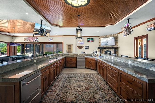 kitchen featuring wood ceiling, pendant lighting, a fireplace, a tray ceiling, and kitchen peninsula