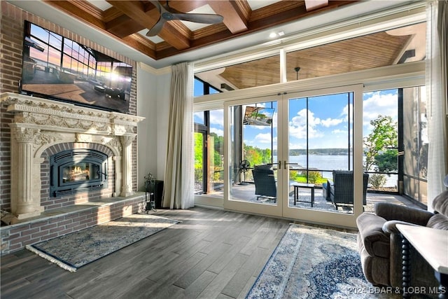 interior space featuring hardwood / wood-style flooring, a brick fireplace, a water view, ceiling fan, and coffered ceiling