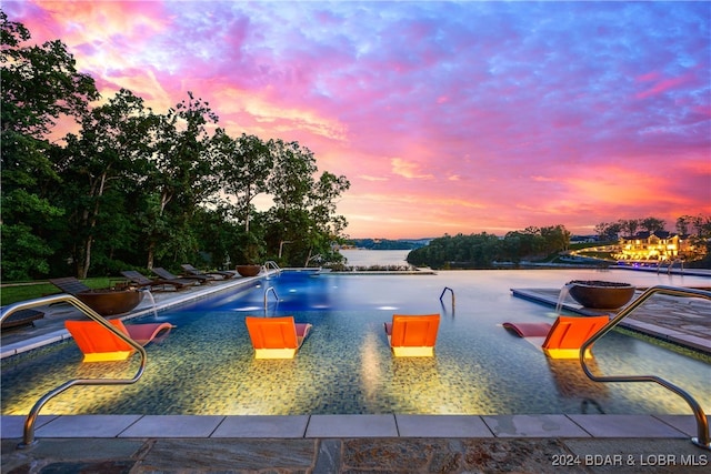 pool at dusk with pool water feature and a water view