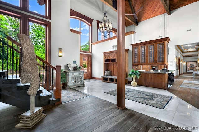 entryway featuring beam ceiling, wooden ceiling, high vaulted ceiling, a notable chandelier, and wood-type flooring