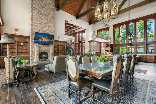 dining space with high vaulted ceiling, beamed ceiling, a stone fireplace, and dark hardwood / wood-style floors