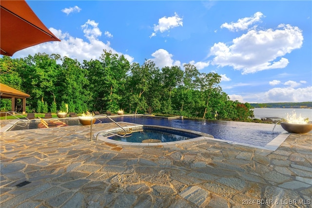 view of pool featuring a jacuzzi, a water view, and a patio area